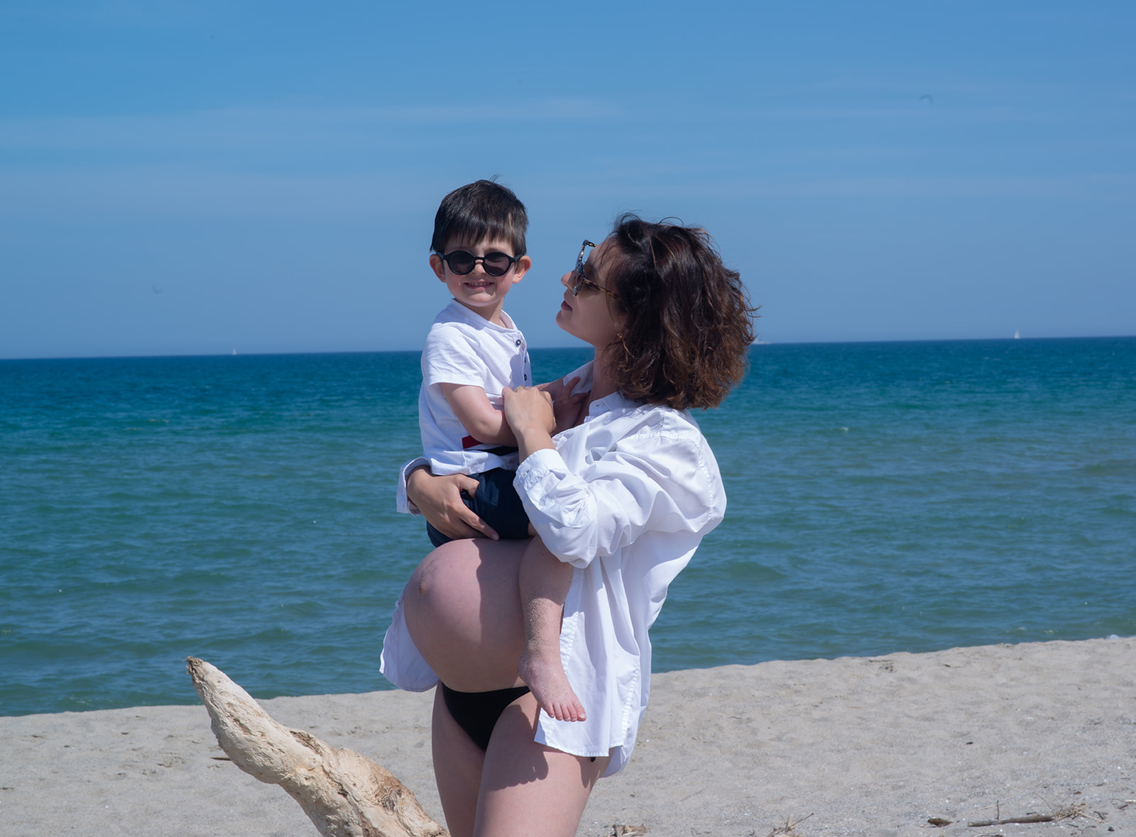 Femme enceinte portant son jeune fils sur la plage